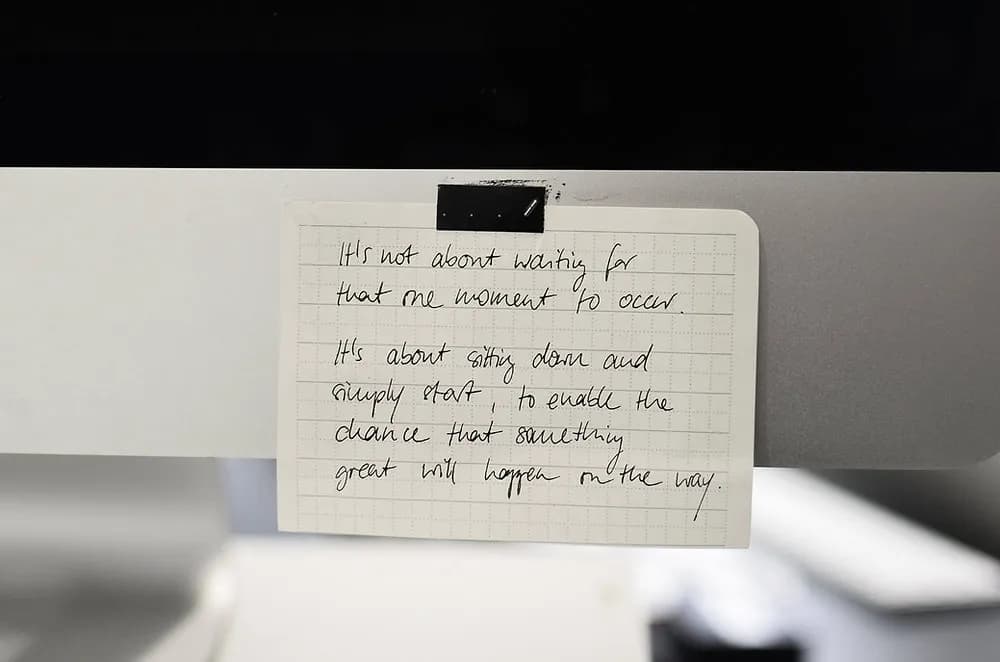 Handschriftliche Notiz auf kariertem Papier am Bildschirm: nicht auf den perfekten Moment warten, sondern einfach anfangen