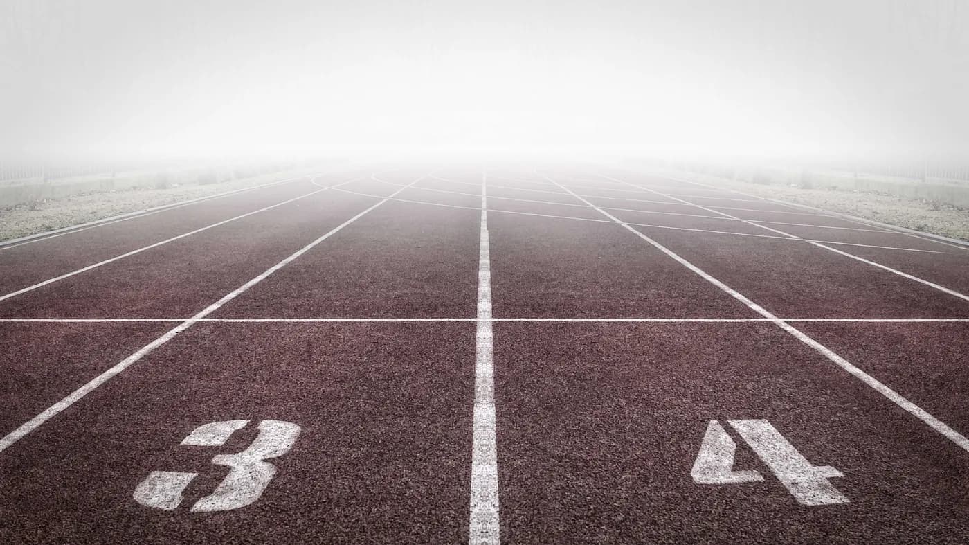 Foggy running track with lanes numbered 3 and 4 stretching into the mist
