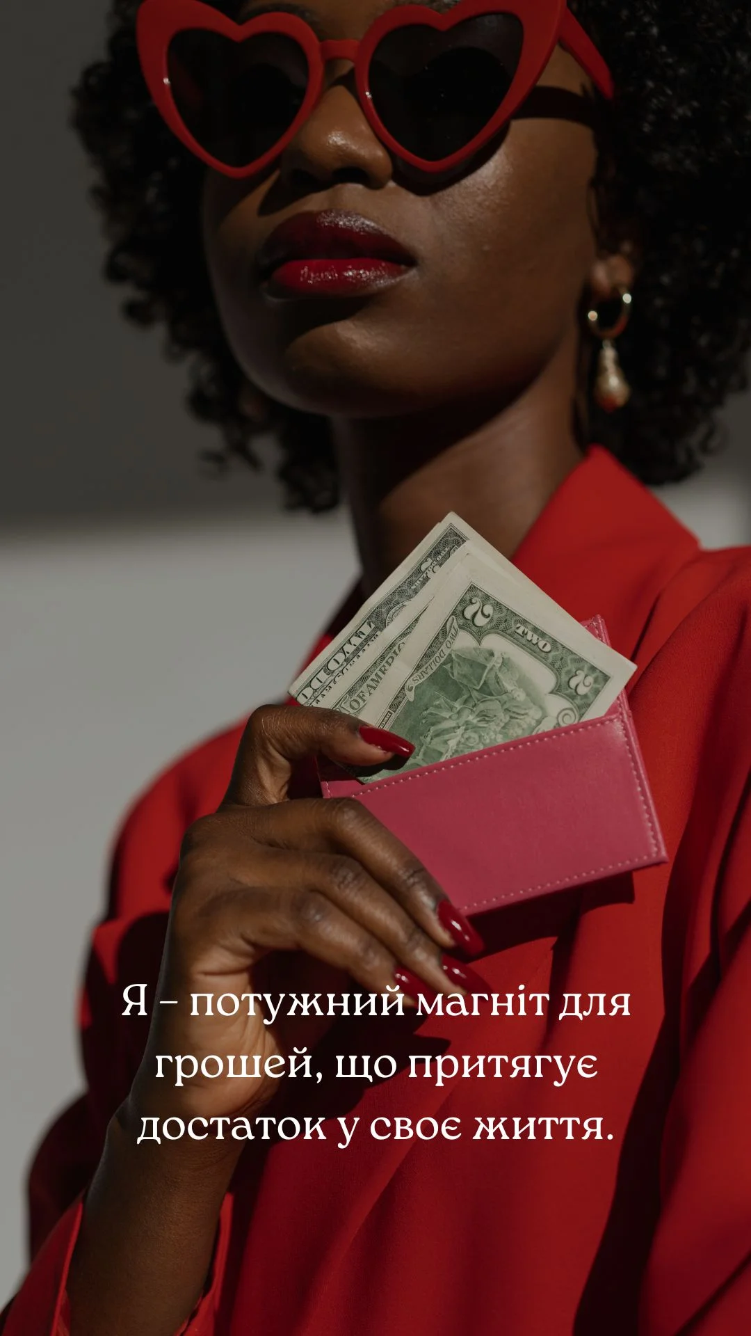 Картка грошової афірмації: жінка в червоному дістає доларові купюри з рожевого гаманця, із написом «Я – потужний магніт для грошей, що притягує достаток у своє життя.»