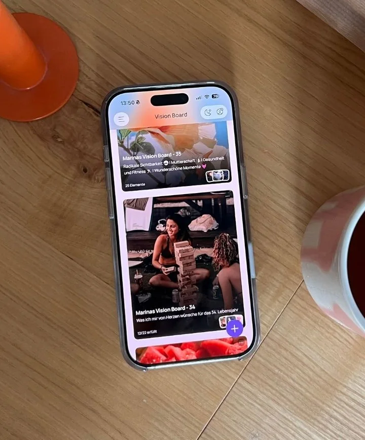 Mein iPhone auf einem Holztisch mit meinen beiden eigenen Jahres-Boards in VISIYA, daneben eine Kerze und eine Tasse Tee