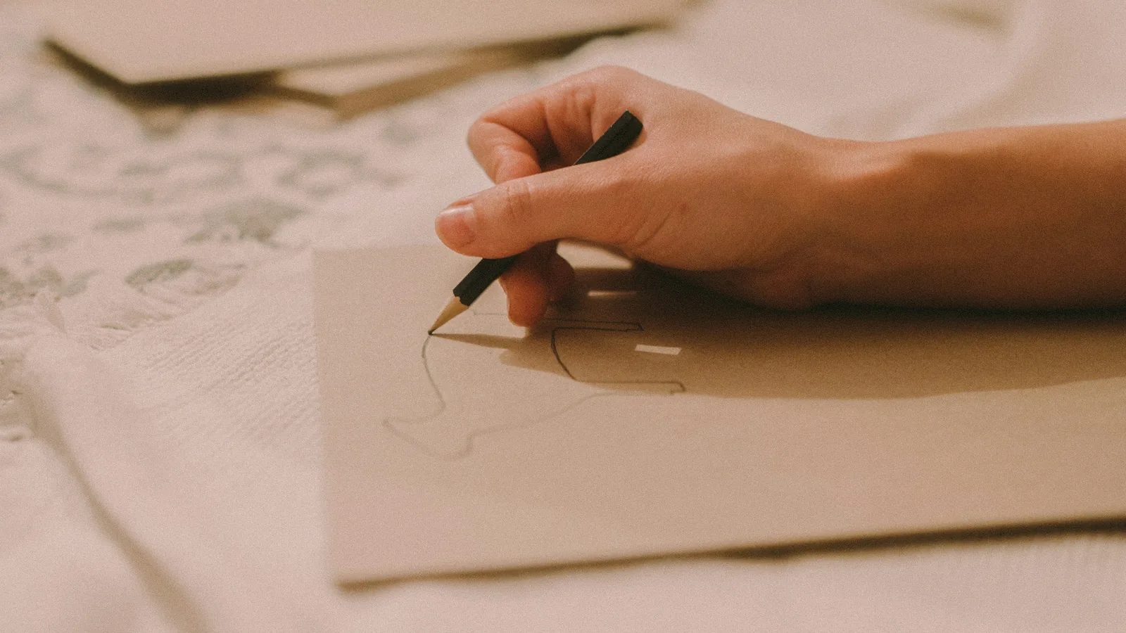 A hand with a pencil on a small card, more cards behind it