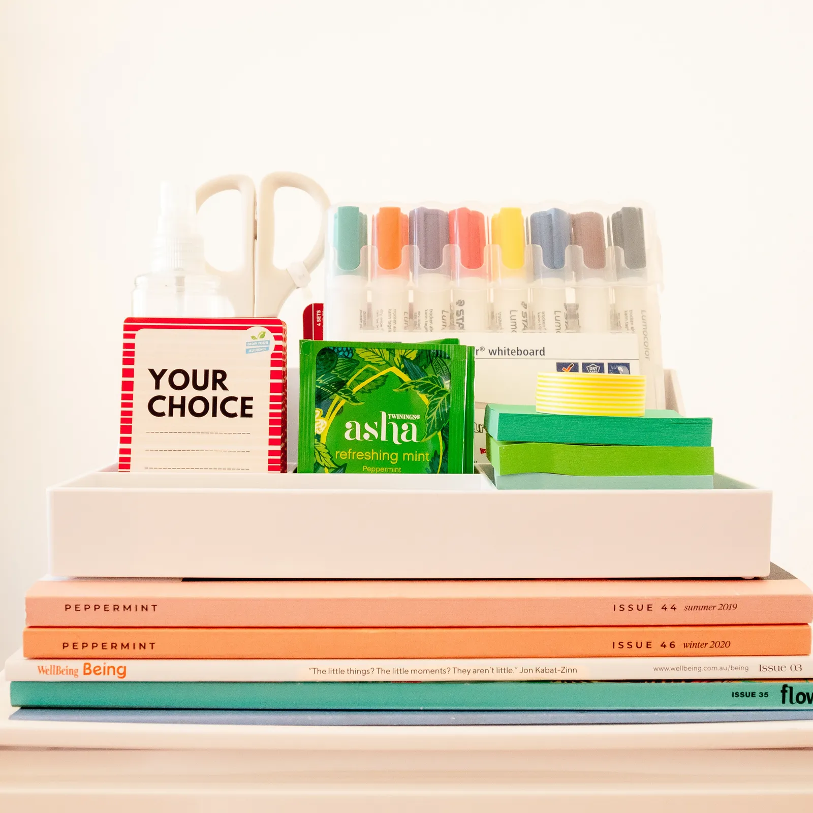 Pens, stationery and magazines laid out on a tray for a vision board party