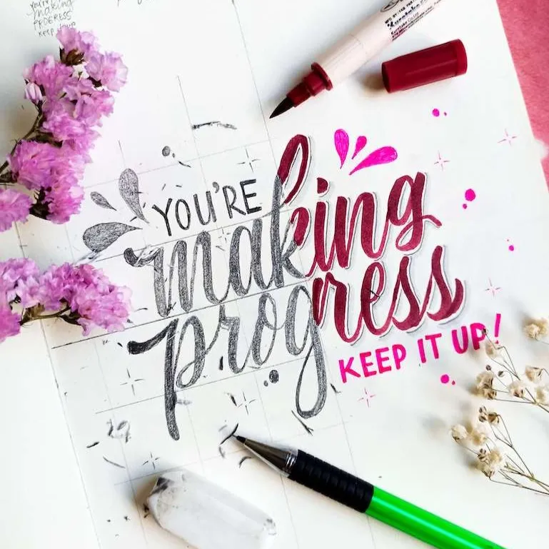 A hand-lettered note reading "You're making progress! Keep it up!" surrounded by flowers and pens