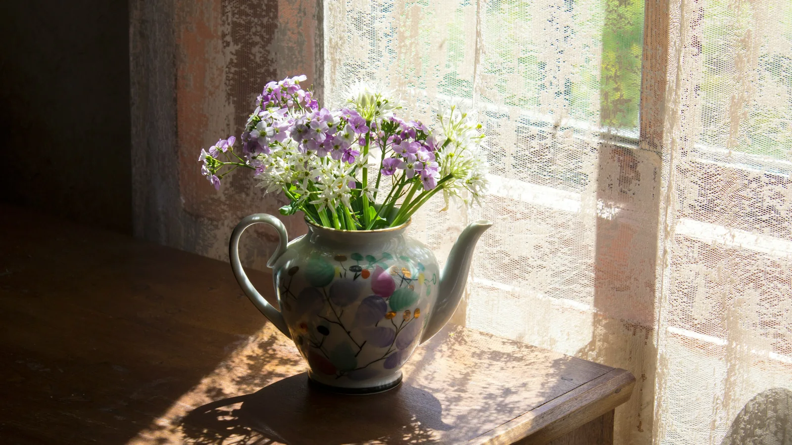 Wildflowers in a teapot by a sunny window