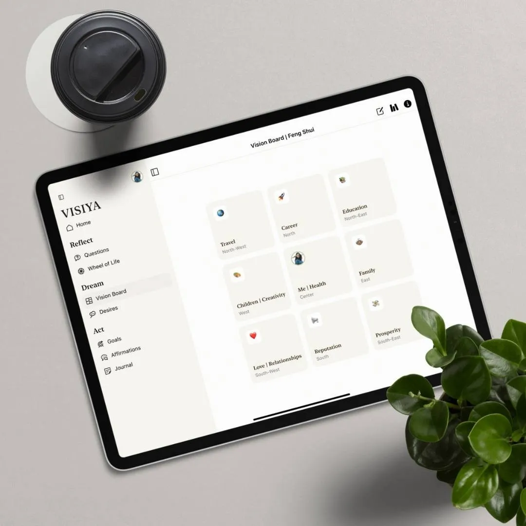 VISIYA app on a tablet showing a Feng Shui vision board in Bagua sectors, beside coffee and a plant