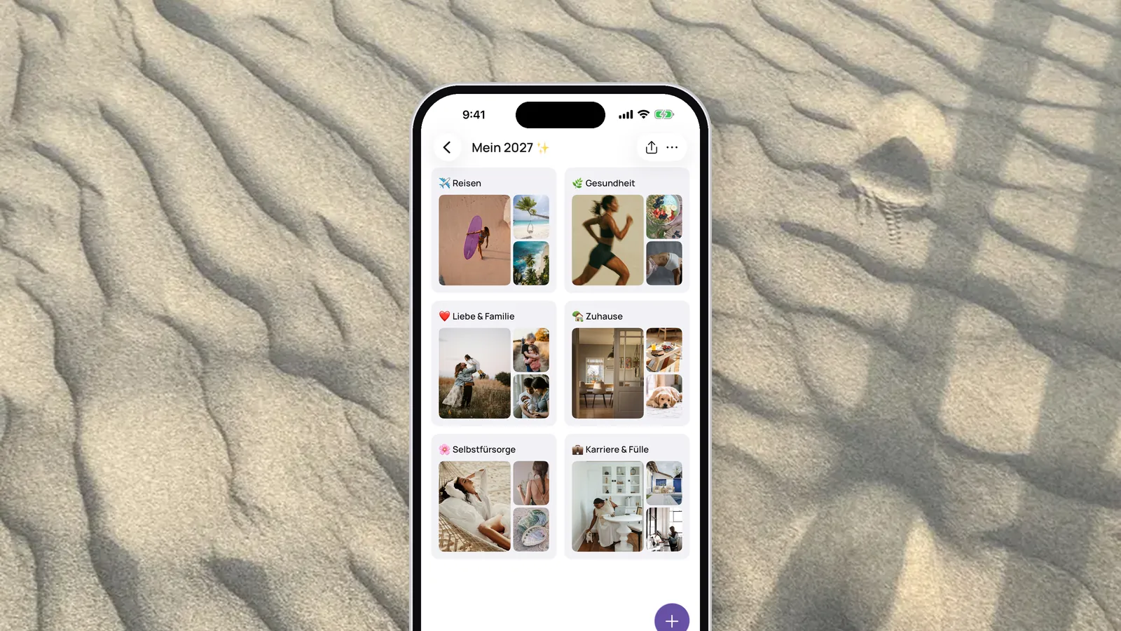 Ein iPhone mit einem VISIYA Vision Board mit sechs Bereichen, von Reisen und Gesundheit bis Karriere & Fülle, auf gewelltem Sand