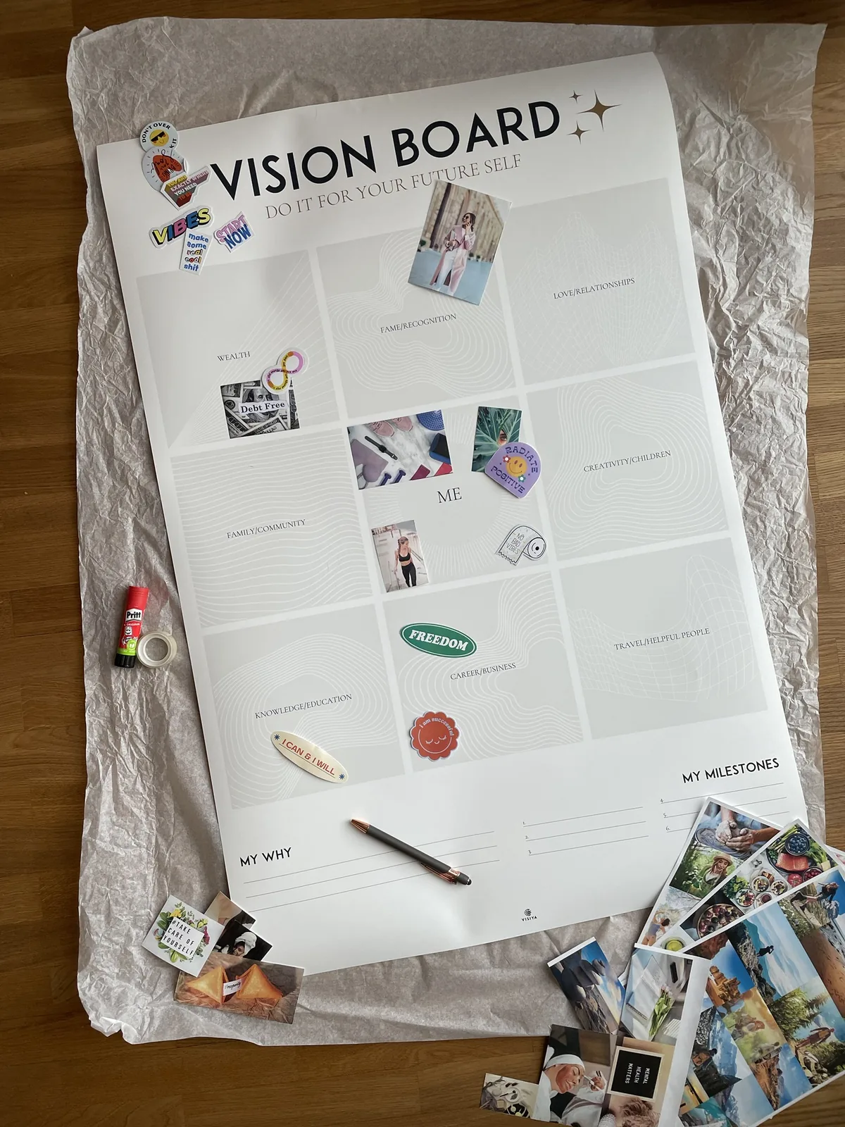 My paper vision board in progress: a printed poster with the Bagua areas, the first cutouts and stickers, glue and tape beside it