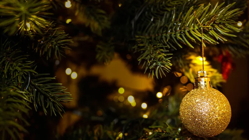 Eine goldene Christbaumkugel in einem beleuchteten Weihnachtsbaum