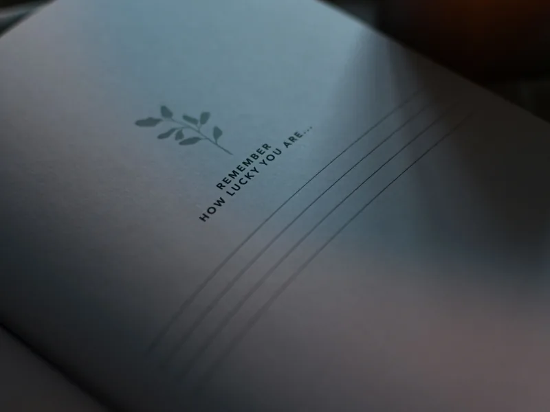 Ein aufgeschlagenes Notizbuch im weichen Licht mit dem Satz „Remember how lucky you are“